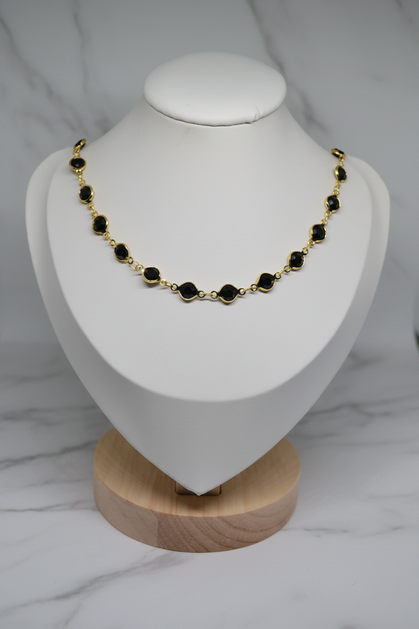 Collier pierres noires serties or — Buste fond marbre blanc
